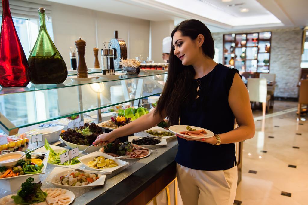แกรนด์ เมอร์เคียว เรสซิเดนซ์ อาบู ดาบี Aparthotel อาบูดาบี ภายนอก รูปภาพ A woman selecting food from a buffet
